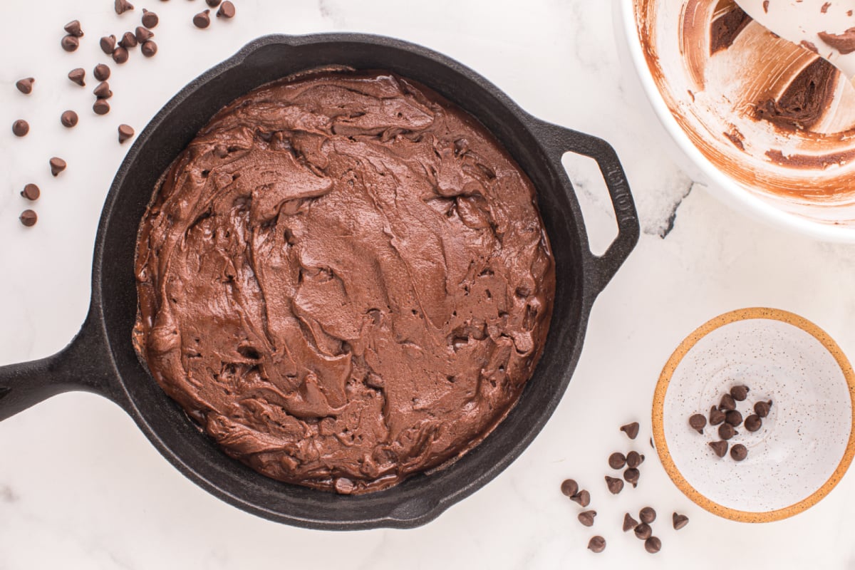 brownie batter placed in cast iron skillet