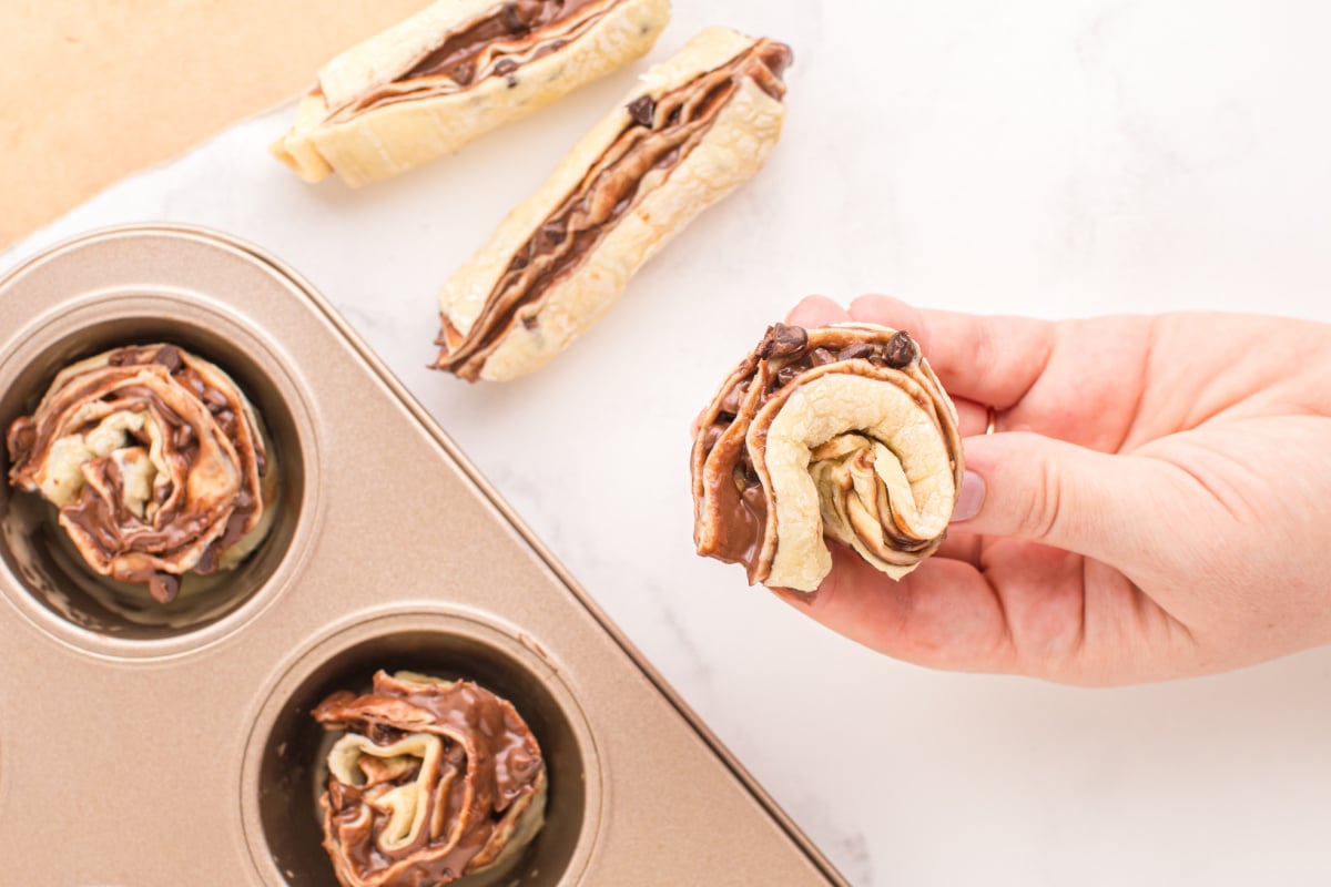 placing rolled up pasty into muffin tin