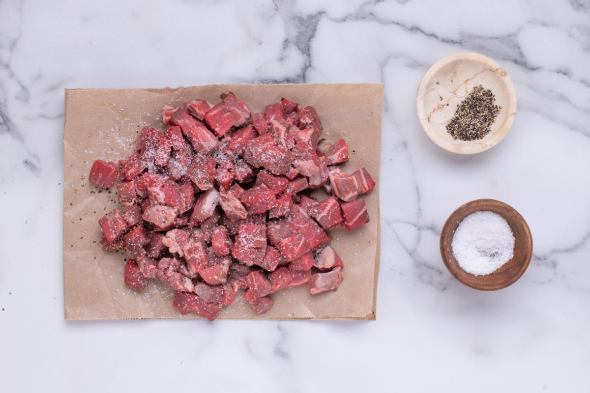 chopped beef on parchment paper seasoned with salt and pepper