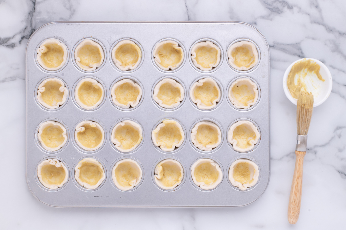 mustard brushed into pasty cups in muffin pan