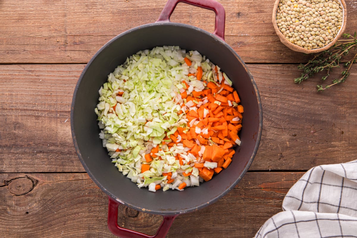 onion, carrots, and cabbage in a soup pot