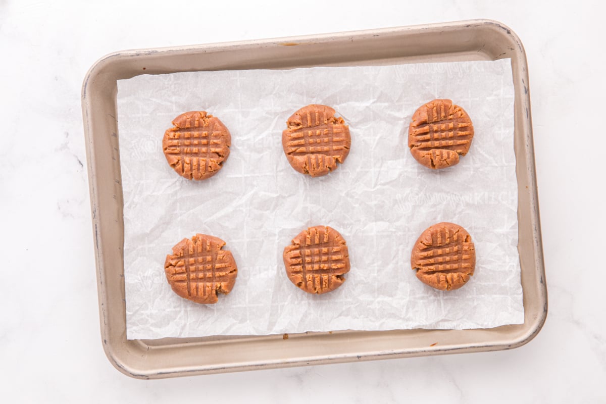 flattened cookie dough balls on baking sheet