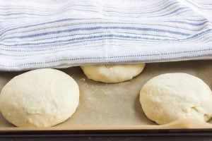 dough balls on baking sheet and covered with a towel