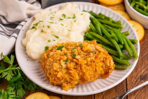 Baked Ritz Pork Chops on a plate with green beans and mashed potatoes