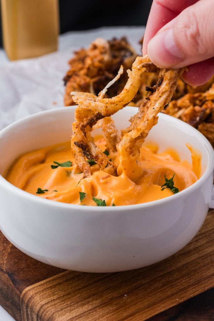 dipping Air Fryer Onion Strings in sauce
