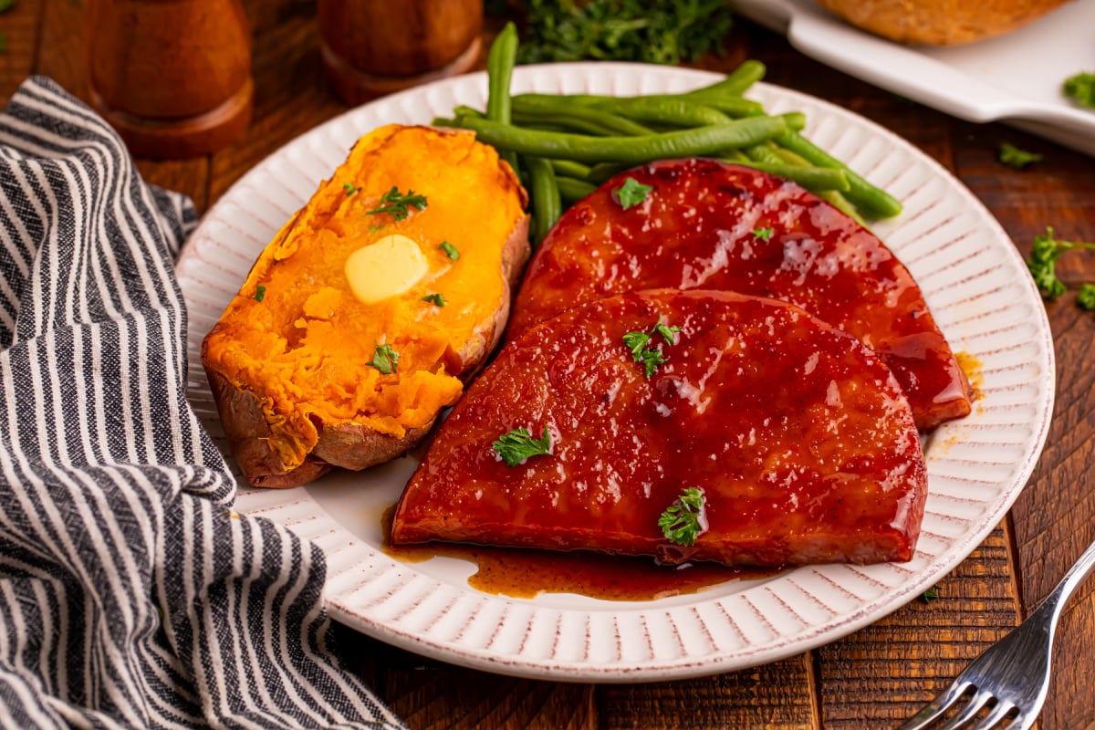 maple glazed ham steaks  on a plate with potato and green beans