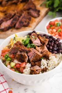 Copycat Chipotle Steak in a bowl with rice, bean salsa and avocado
