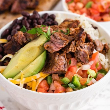 Copycat Chipotle Steak in a bowl with rice, bean salsa and avocado
