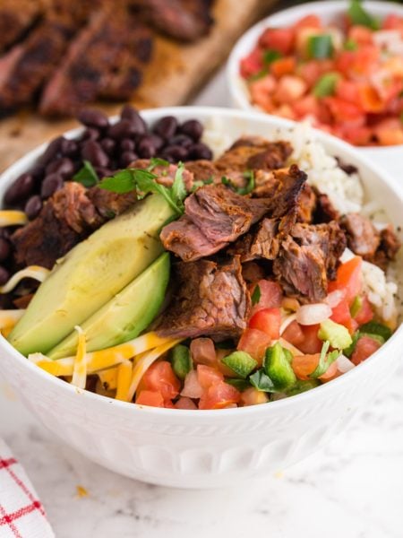 Copycat Chipotle Steak in a bowl with rice, bean salsa and avocado