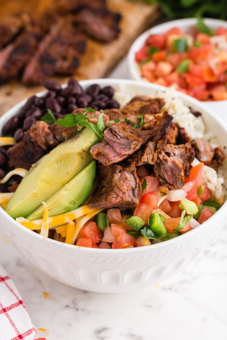 Copycat Chipotle Steak in a bowl with rice, bean salsa and avocado