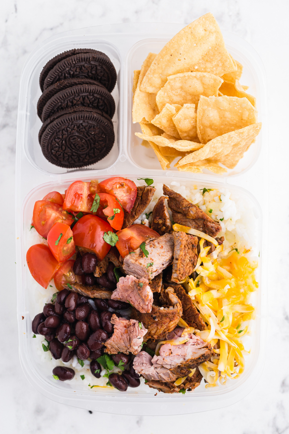 leftover copycat chipotle steak in a lunchbox with chips and cookies