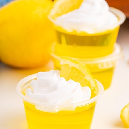 Lemon Drop Jello Shots topped with whipped cream and lemon slice