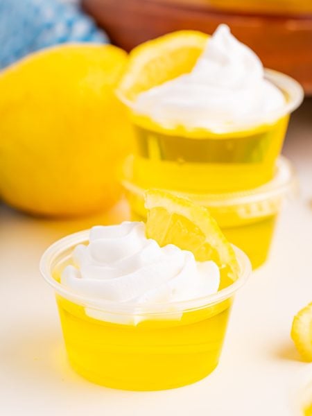 Lemon Drop Jello Shots topped with whipped cream and lemon slice