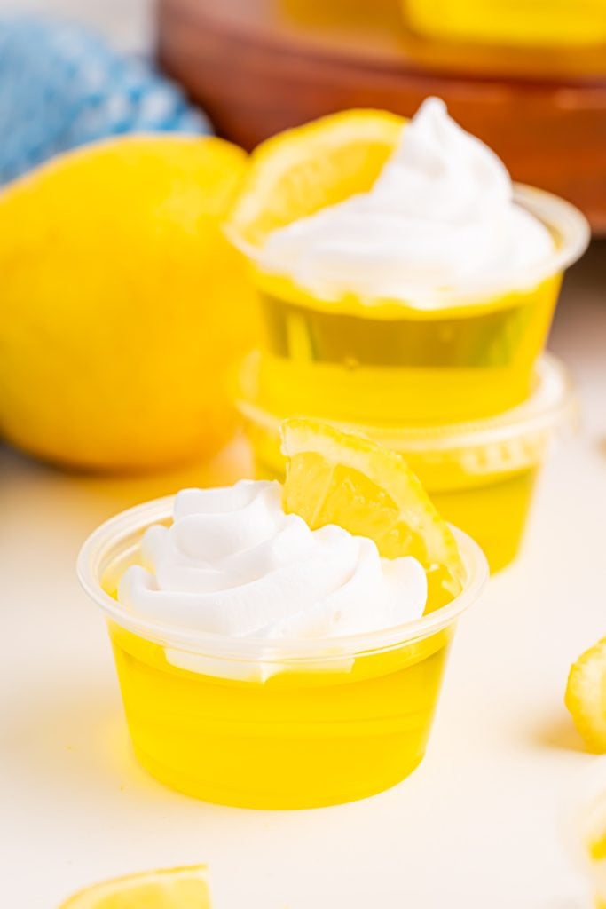 Lemon Drop Jello Shots topped with whipped cream and lemon slice