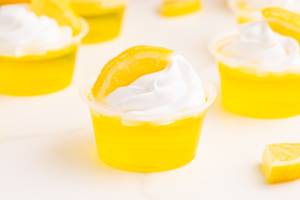 Lemon Drop Jello Shots topped with whipped cream and lemon slice