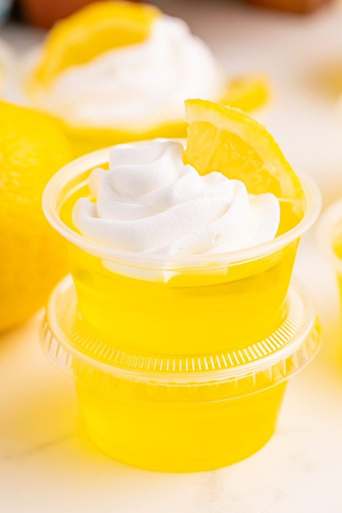 Lemon Drop Jello Shots topped with whipped cream and lemon slice