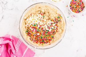 adding sprinkles and white chocolate chips to bowl