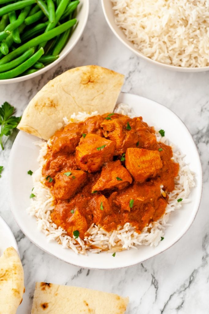 Butter chicken on top of rice with pita bread