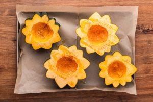 acorn squash cut in half on baking sheet and seasoned