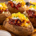 Slow Cooker BBQ Chicken Loaded Baked Potatoes on a cutting board