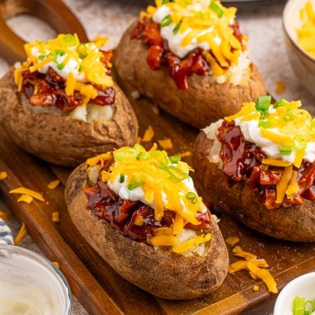 Slow Cooker BBQ Chicken Loaded Baked Potatoes on a cutting board