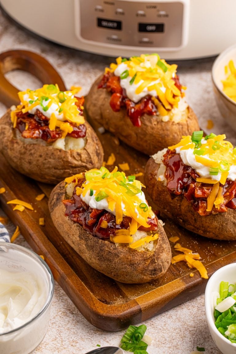 Slow Cooker BBQ Chicken Loaded Baked Potatoes on a cutting board