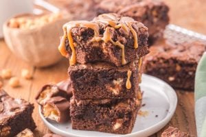 Snickers Brownies stacked on a plate