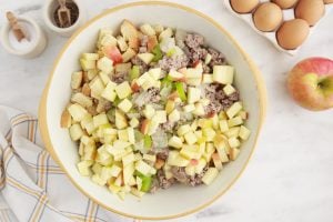 sausage mixture, apples and bread added to a bowl together