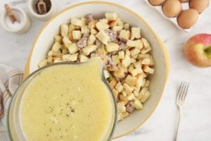 egg mixture in mixing bowl being poured over stuffing mixture