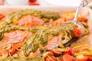 Sheet Pan Pesto Salmon Dinner being scooped up with a serving spoon