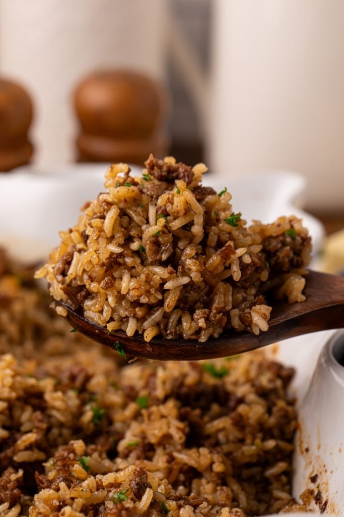 Spoon buttery beef and rice casserole with a wooden spoon