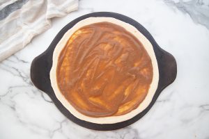 peanut sauce spread on pizza crust