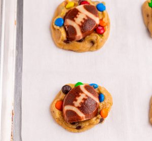 placing football shaped cookies on top of chocolate chip cookies