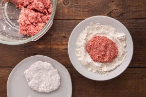 beef patty being dredged in flour