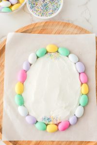 sprinkles and candy covered almonds added to frosting shaped egg
