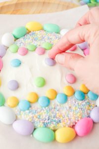 adding m&m's to the top of frosting egg