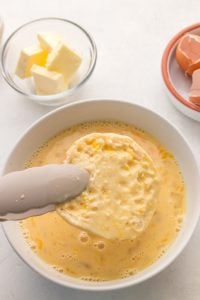 english muffin being placed in egg mixture