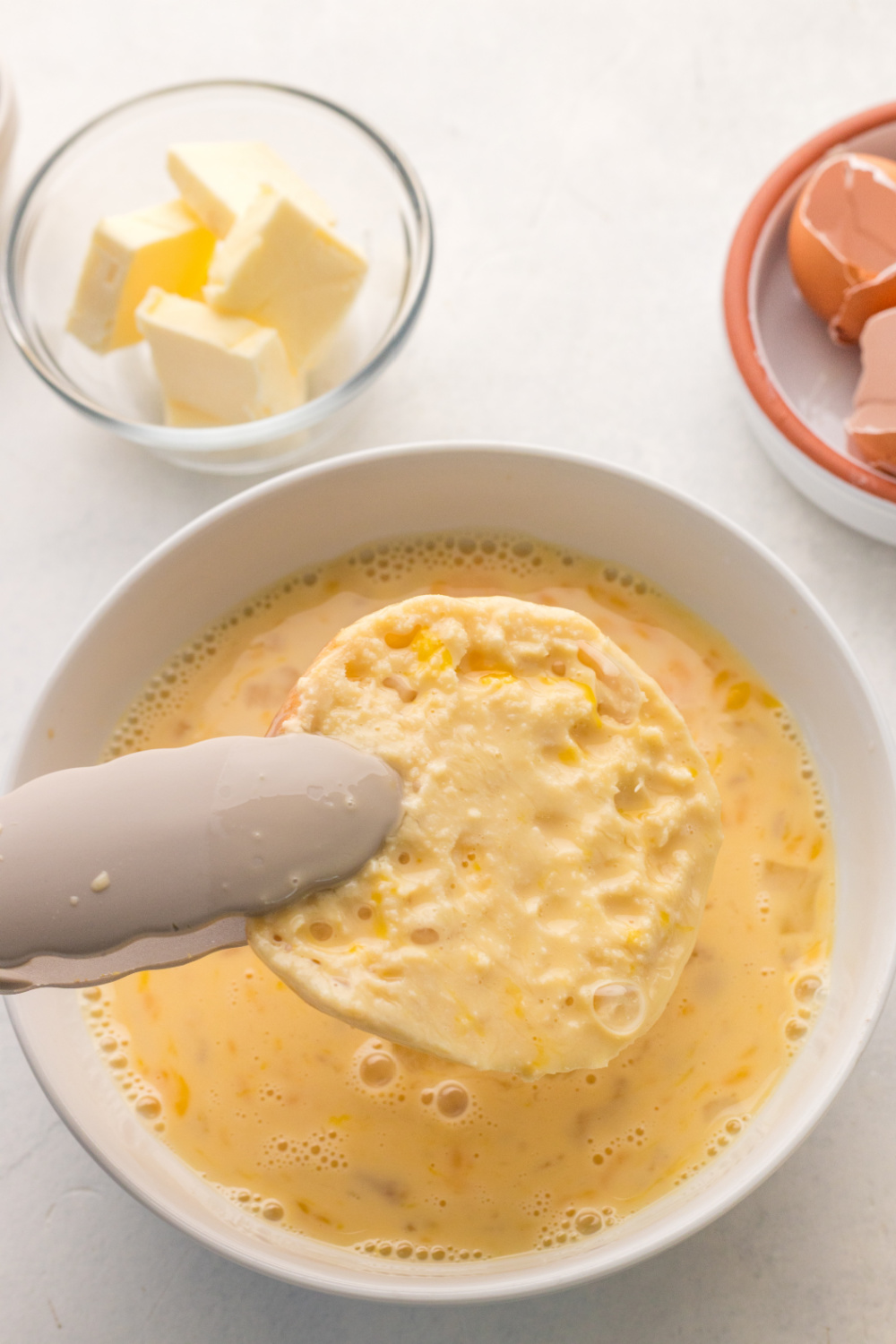 english muffin being placed in egg mixture
