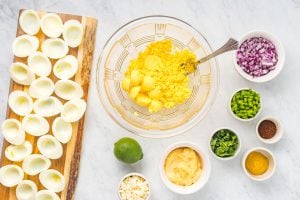 egg yokes in a mixing bowl and ingredient for recipe in other small bowls