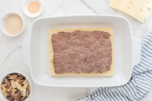 beef patty and bottom half of buns in a baking dish