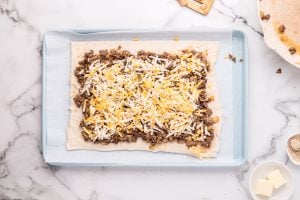 meat mixture and cheese spread on dough