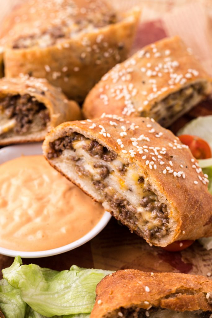 Cheeseburger Garbage Bread on a butting board with sauce