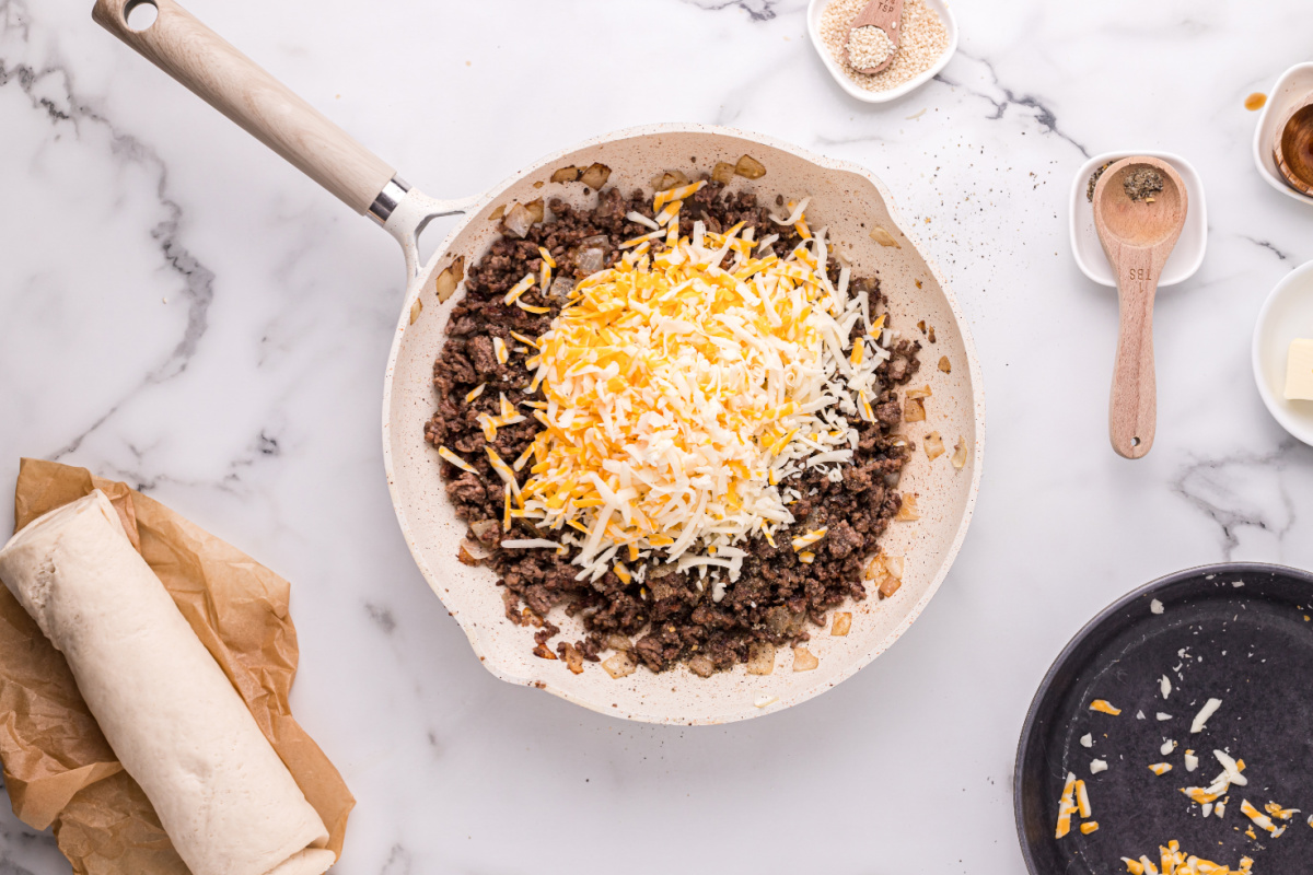 Worcestershire sauce, steak seasoning, and cheese added to pan