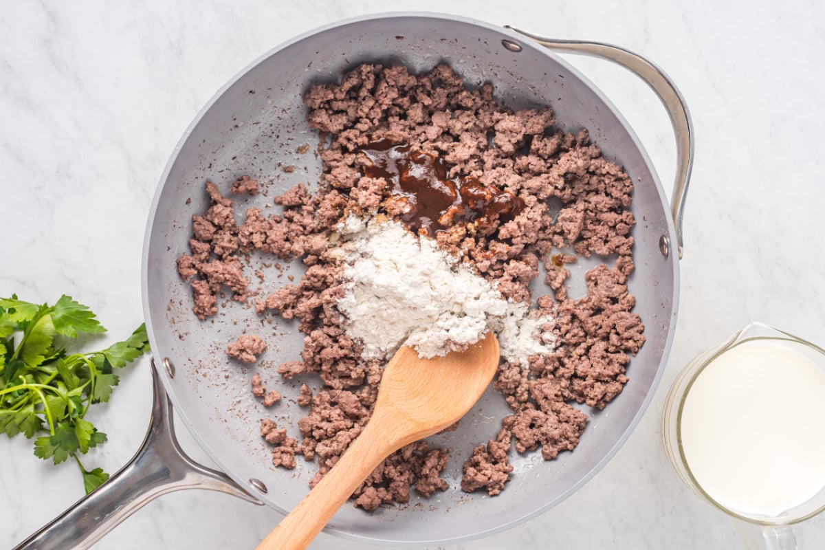 flour, garlic powder, beef bouillon powder, and steak sauce sprinkled over the cooked beef