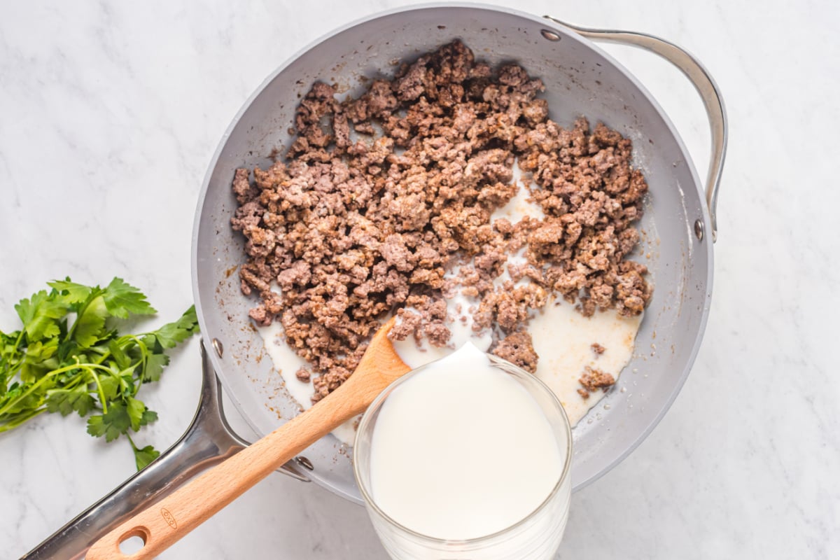 pouring milk over beef mixture