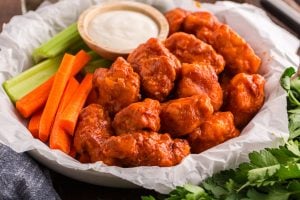 Homemade Crispy Boneless Chicken Wings in a basket with sauce, celery and carrots