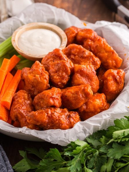 Homemade Crispy Boneless Chicken Wings in a basket with sauce, celery and carrots
