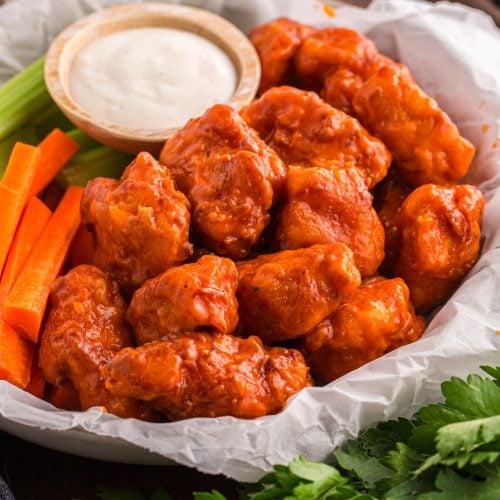 Homemade Crispy Boneless Chicken Wings in a basket with sauce, celery and carrots