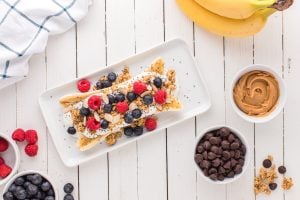 raspberries, blueberries, granola, almond slices, and chia seeds added to top of yogurt and banana