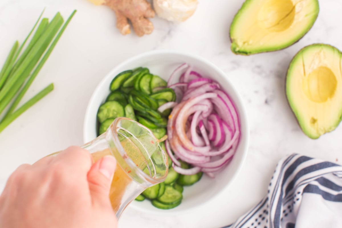 pouring dressing over cucumbers